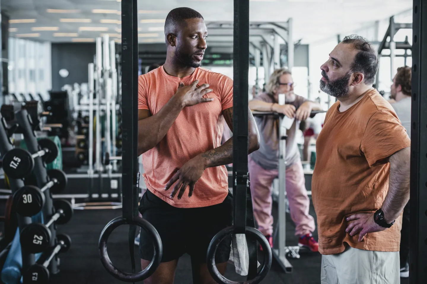 Male personal trainer gives tip a male to on his left while in the gym