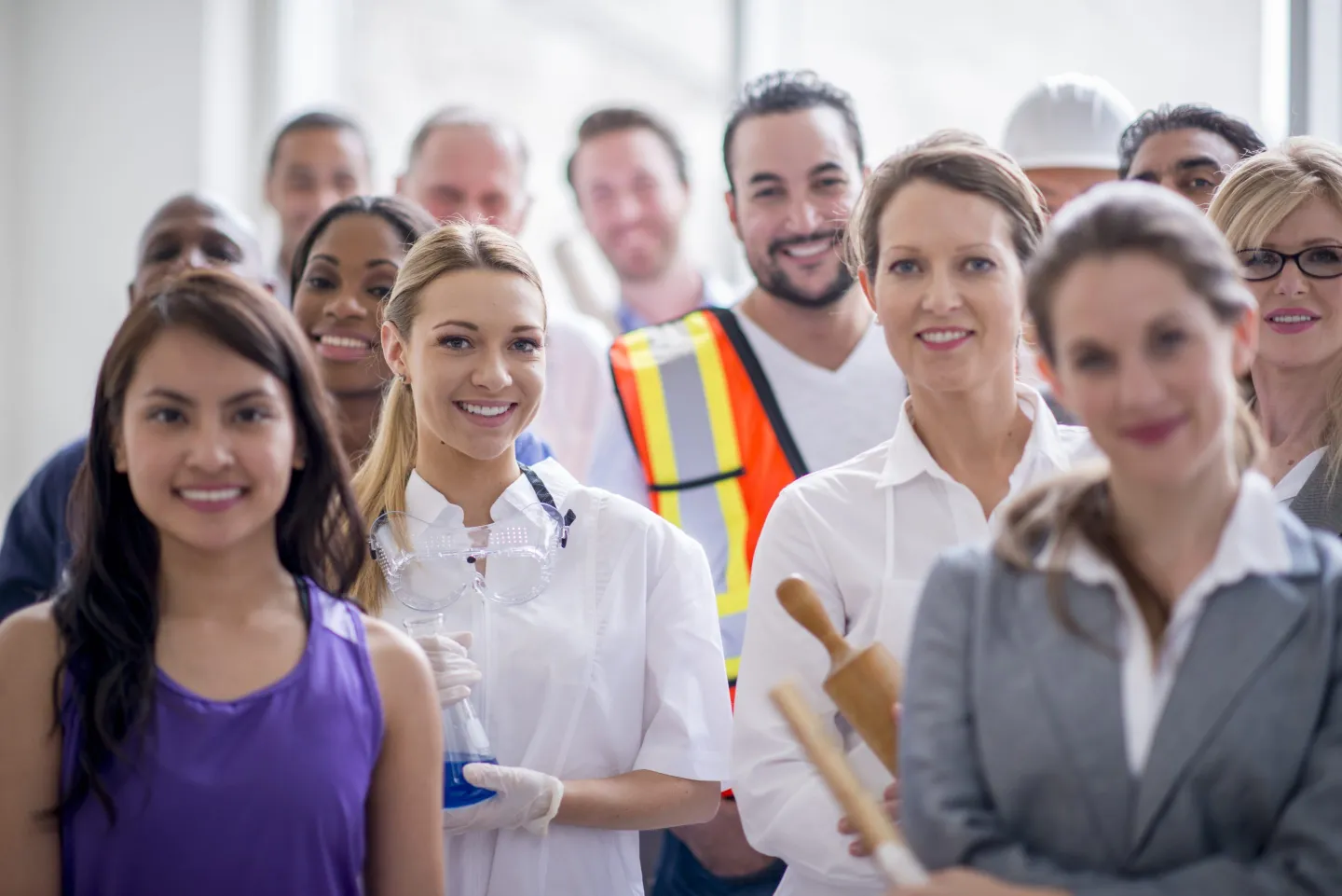 Group of varied professionals stand looking toward the camera.