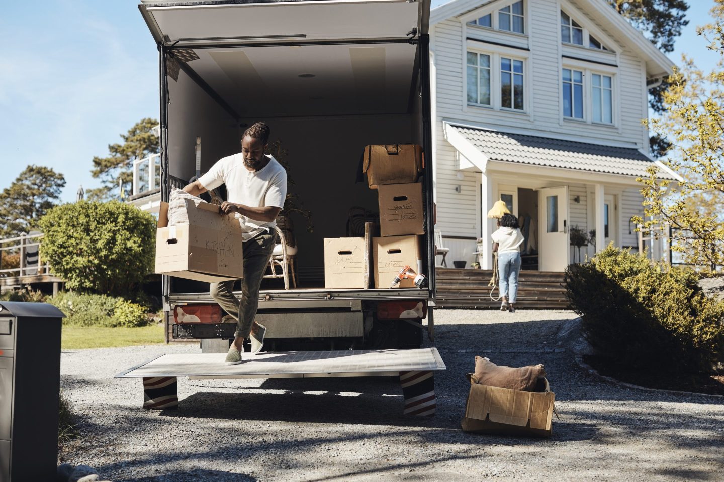 Full length of man unloading cardboard box from van.