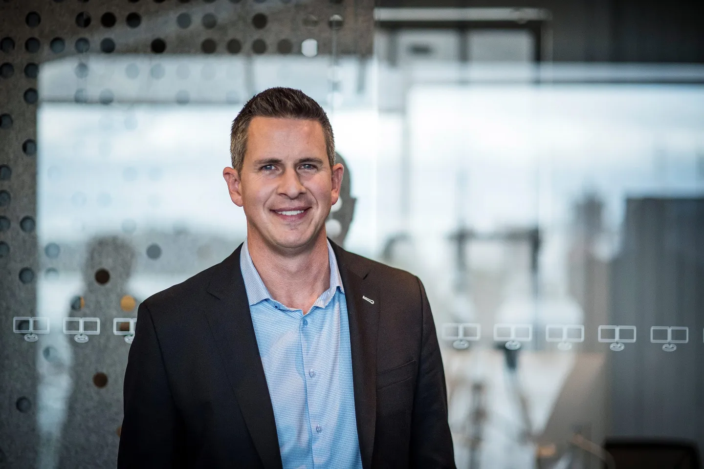 Patrick Spence, now the former CEO of Sonos, smiles in front of a glass window