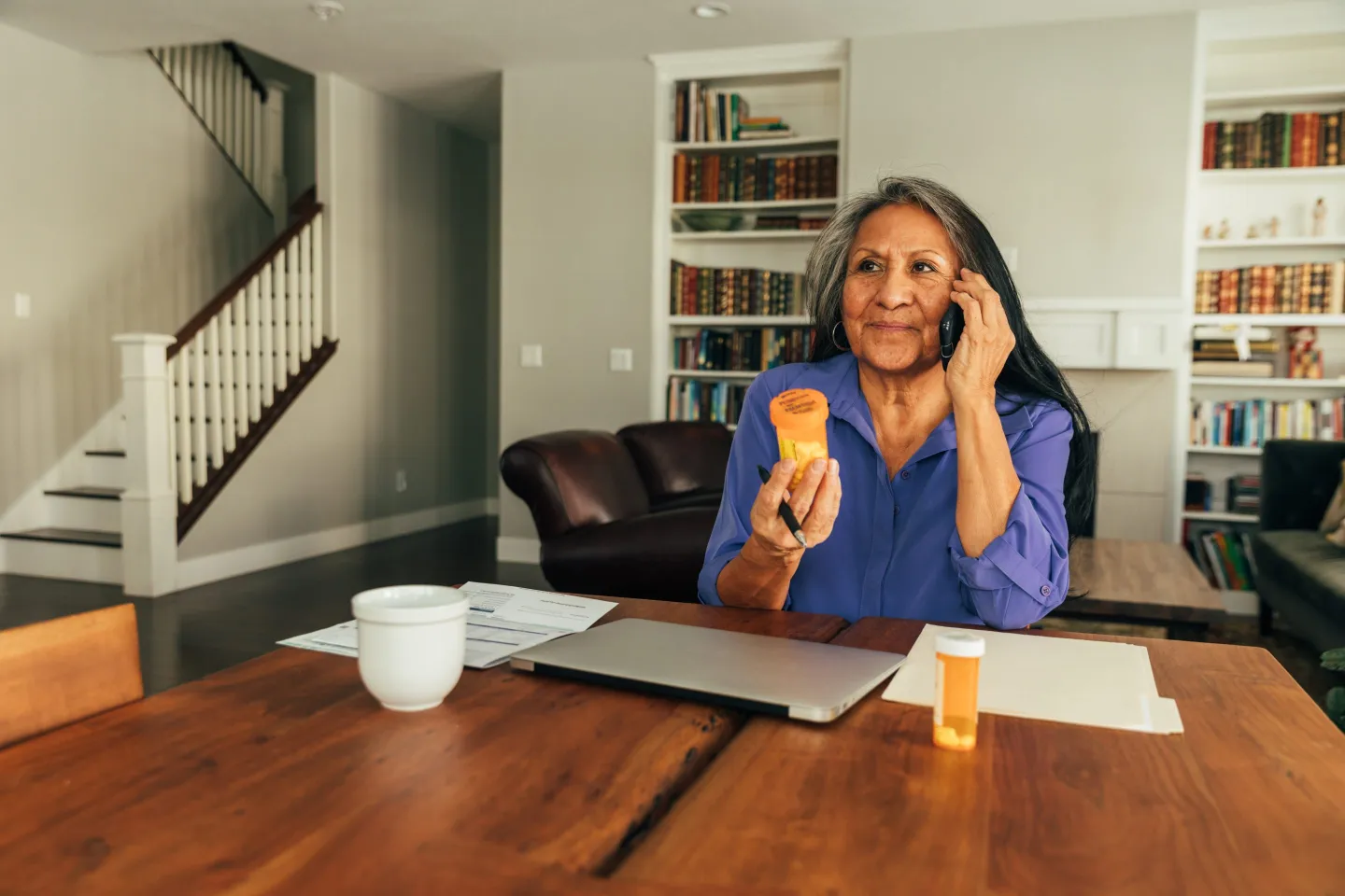 Senior woman talks on the phone while examining paperwork.