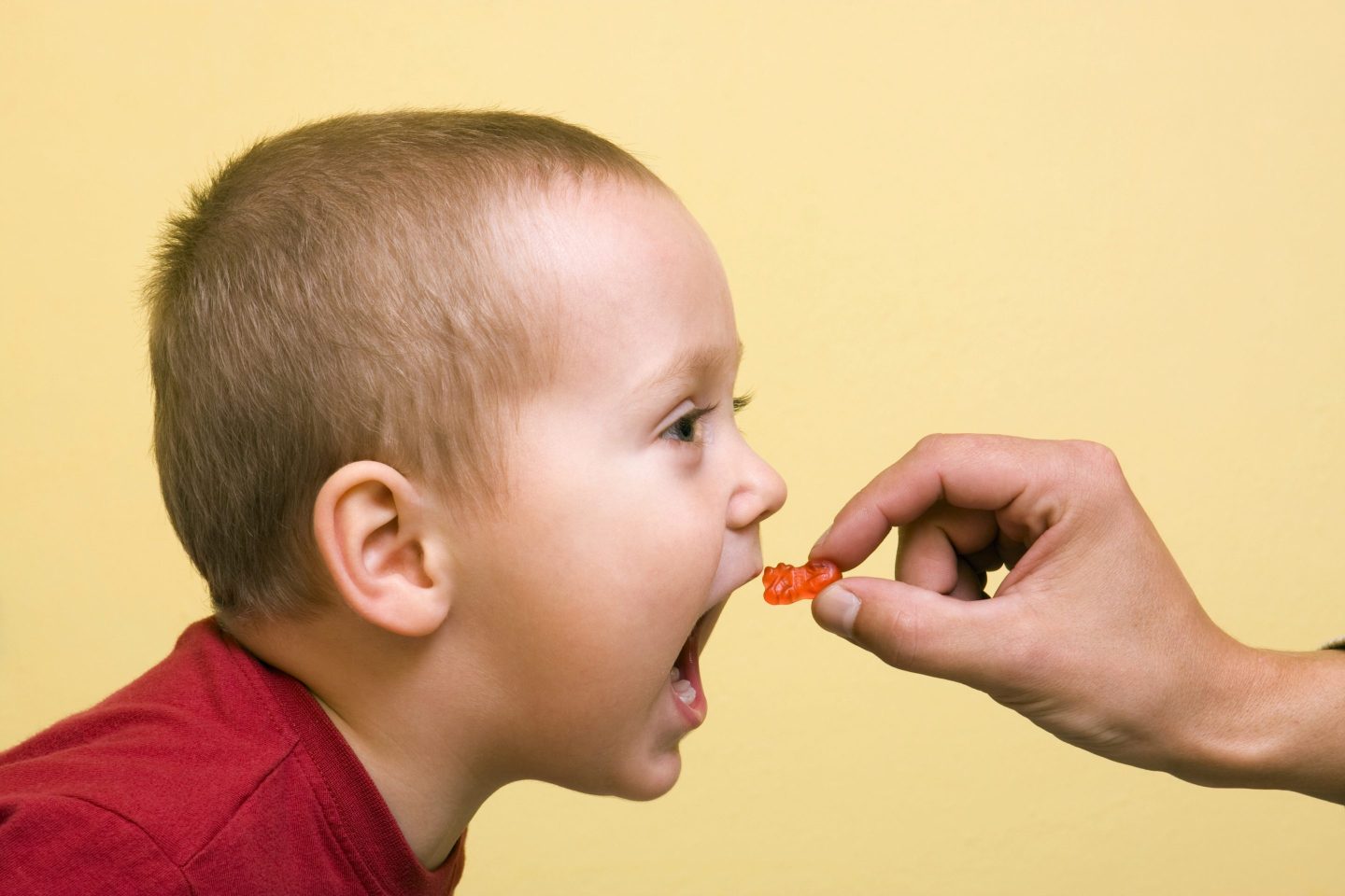 child being fed a gummy from a hand