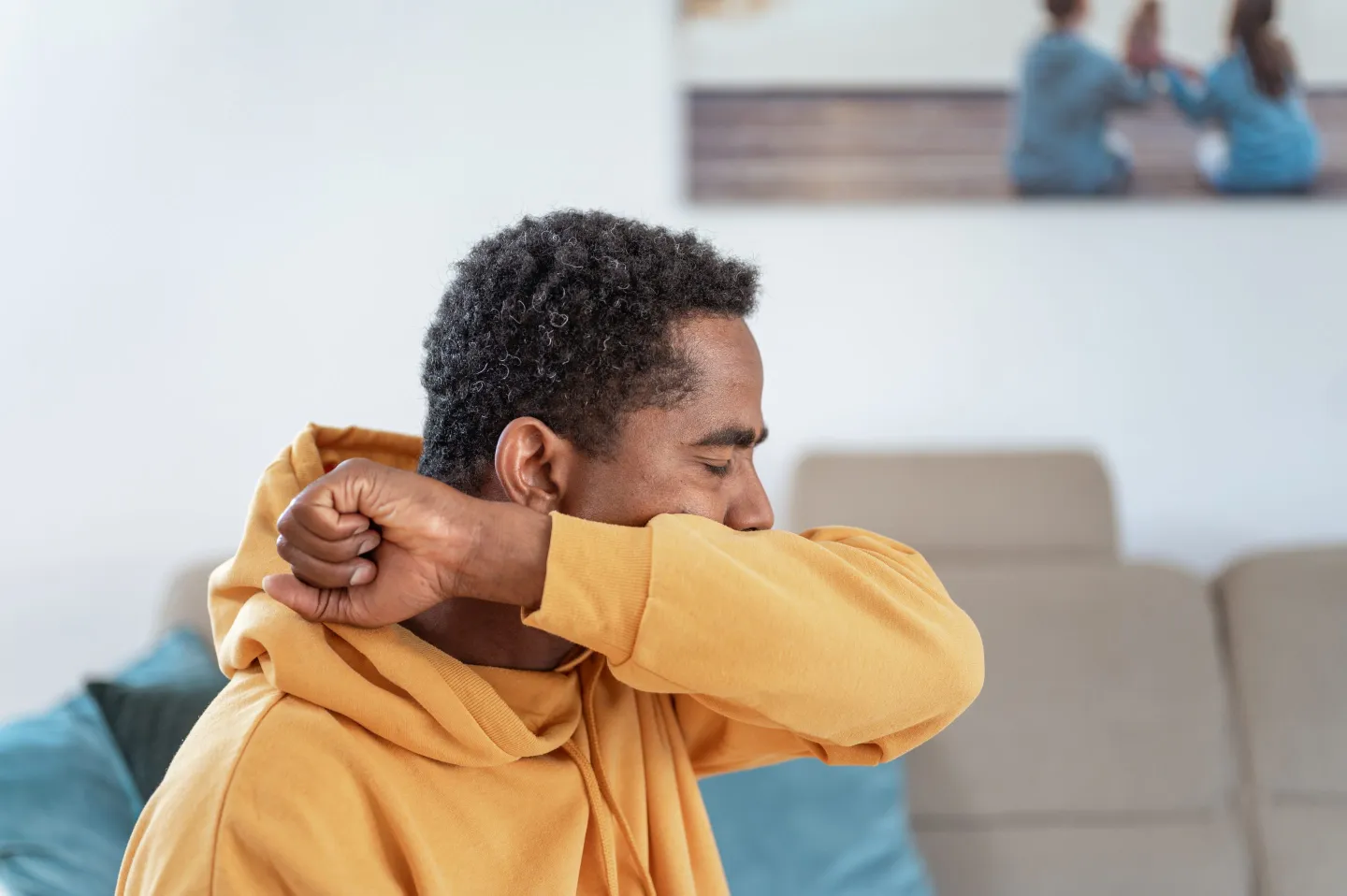 Photo of man coughing or sneezing into his elbow