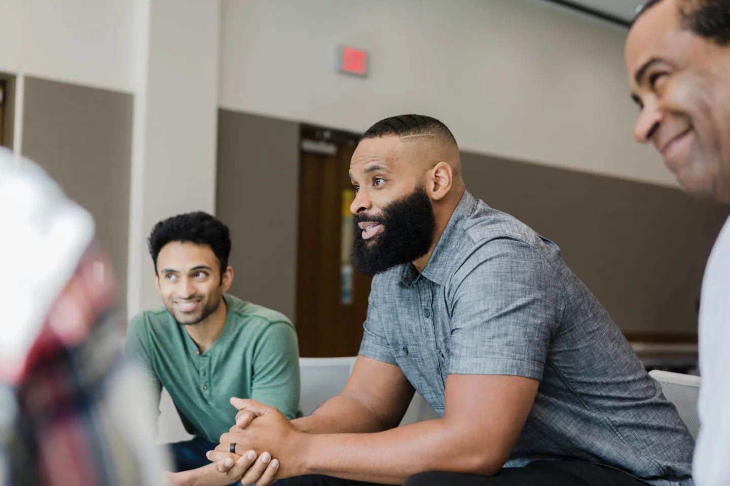 Three men smile during group therapy.