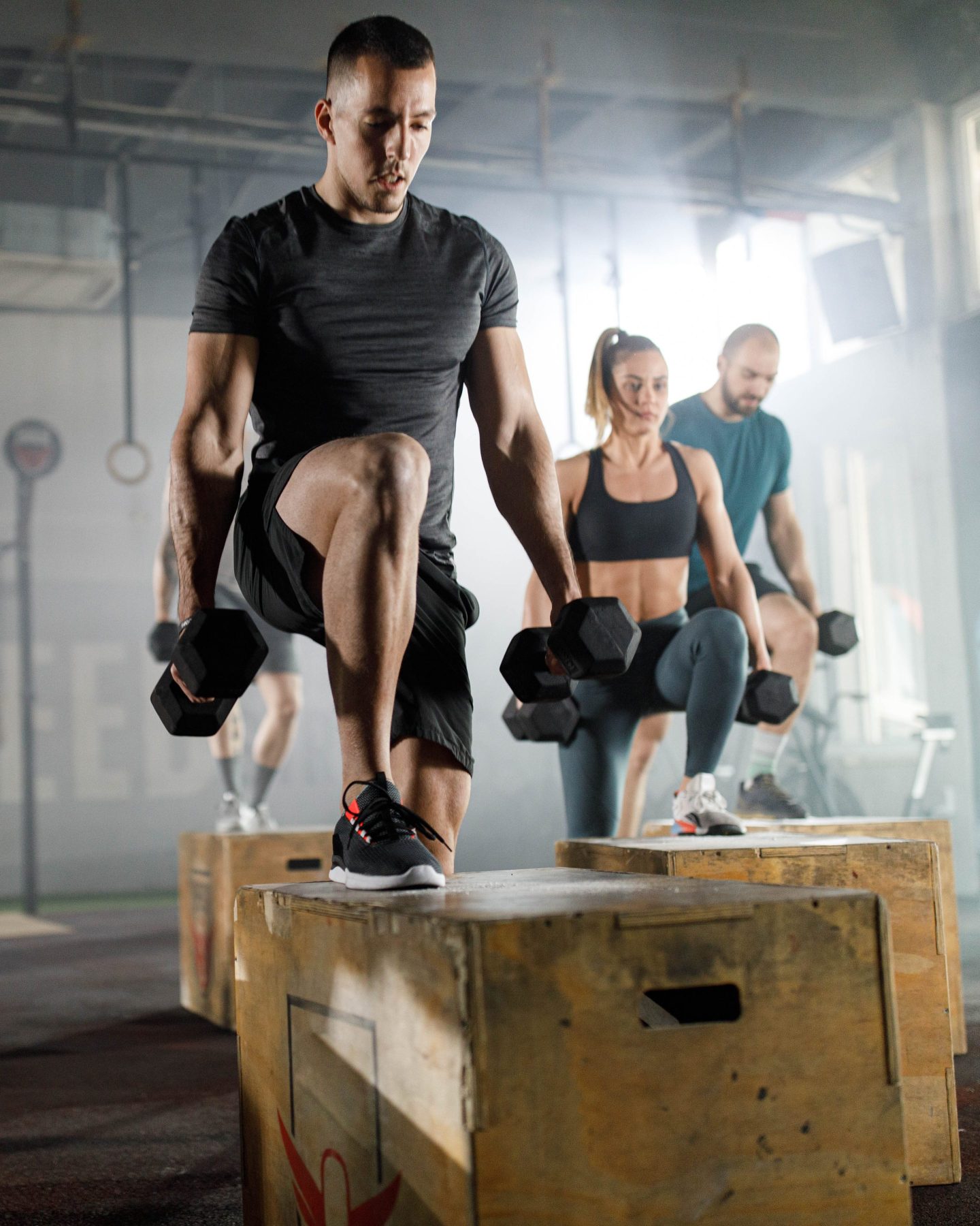 Athletic people having cross training with dumbbells in a gym.