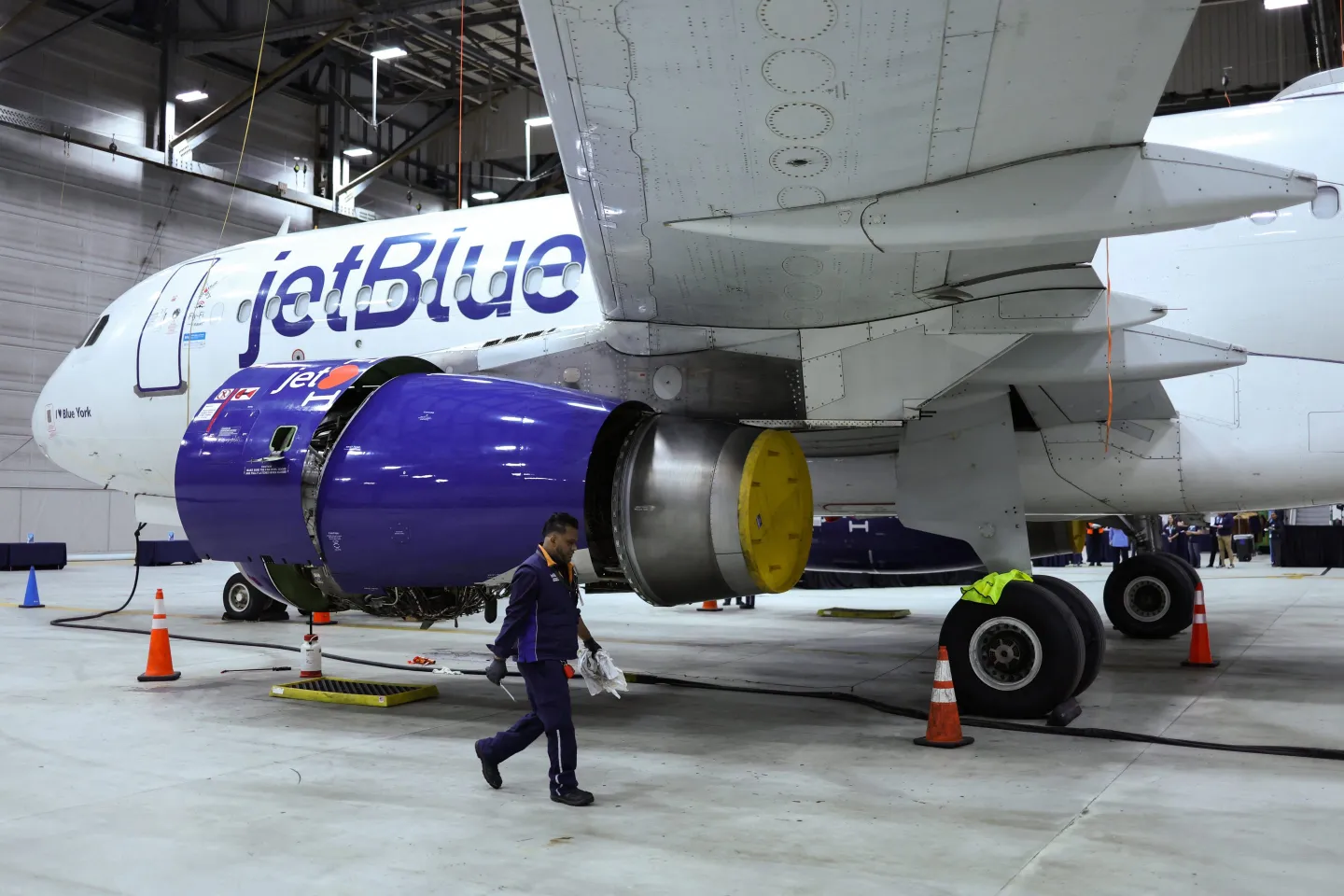 A man in a suit walks past a JetBlue commercial jet.