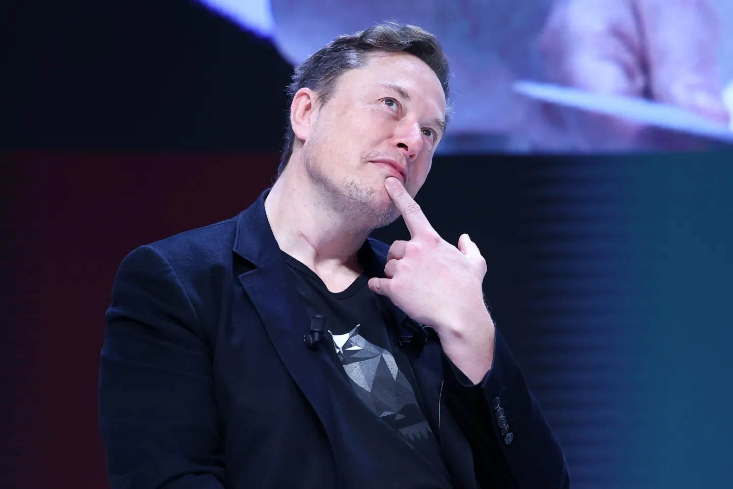 Elon Musk puts his finger on his chin in a thinking face