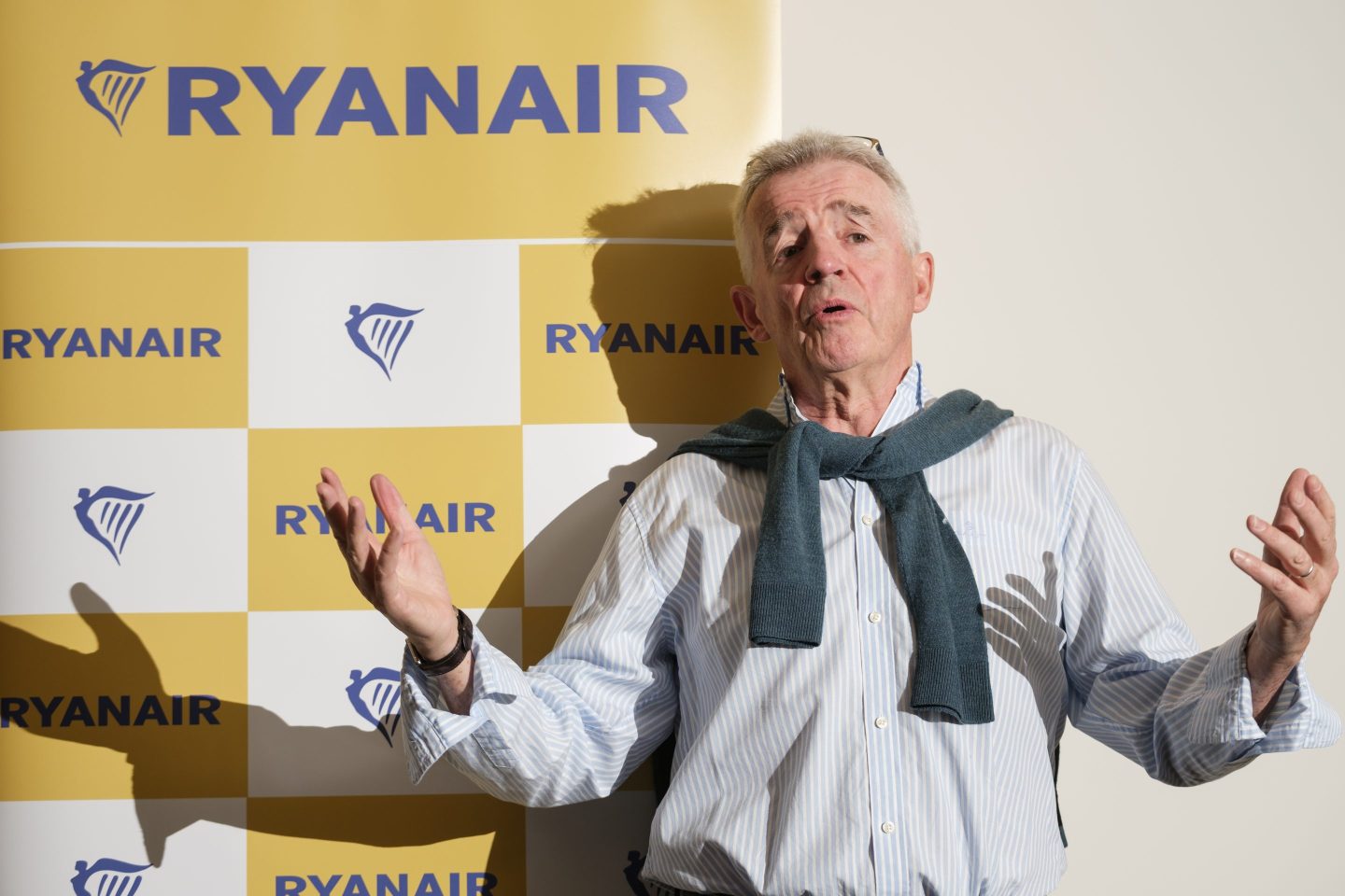 Ryanair CEO Michael O'Leary puts his arms up as he speaks in front of a "Ryanair" backdrop