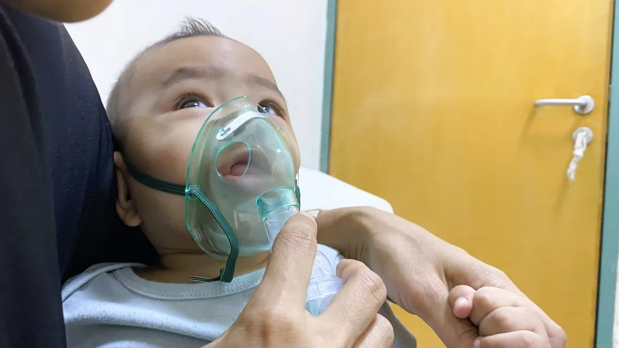 Baby with a nebulizer mask on his face