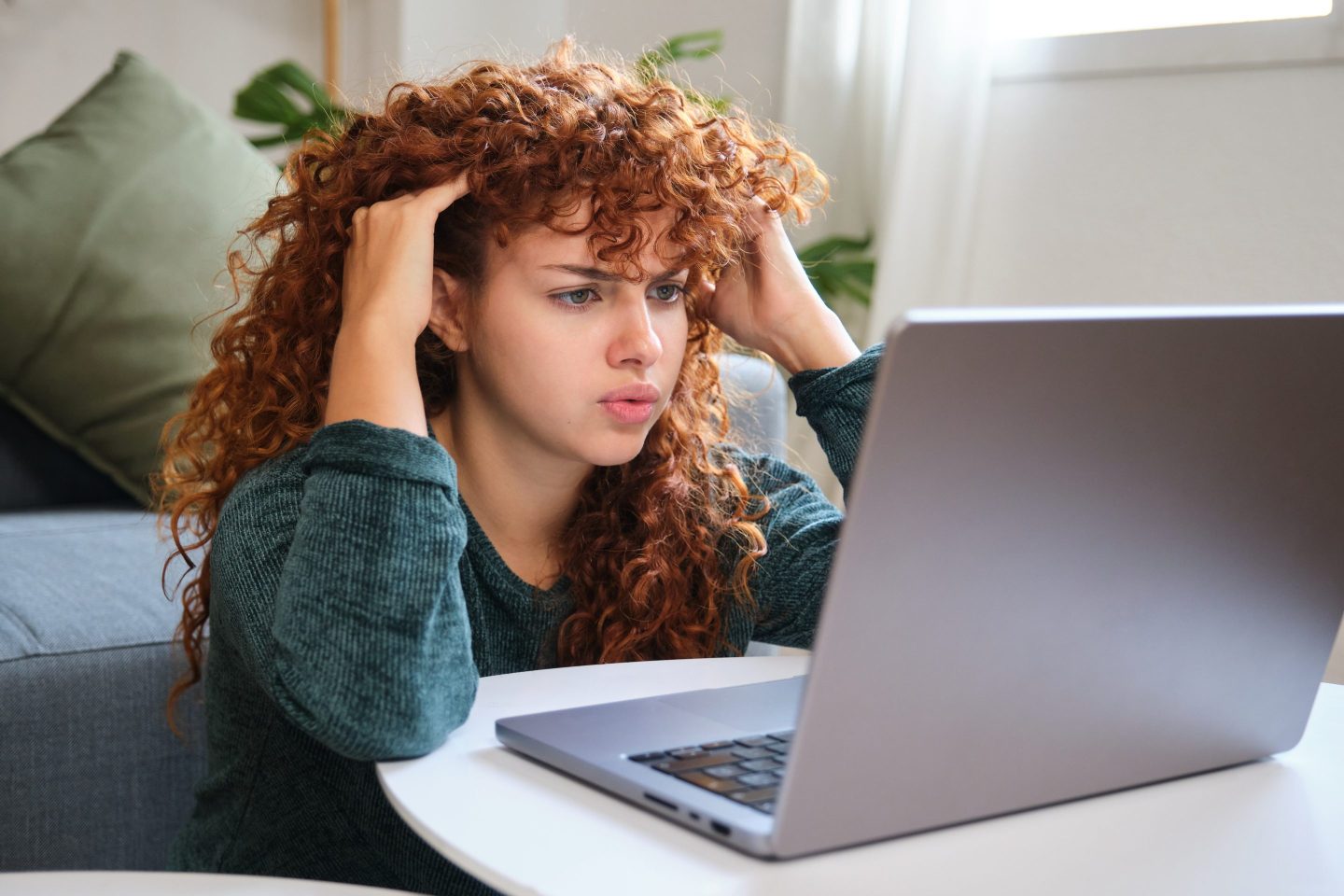 Frustrated freelancer touching hair while working at home office using laptop