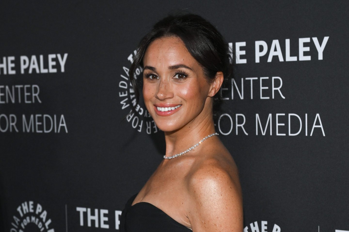 Meghan Markle smiles in front of a gala event in Los Angeles