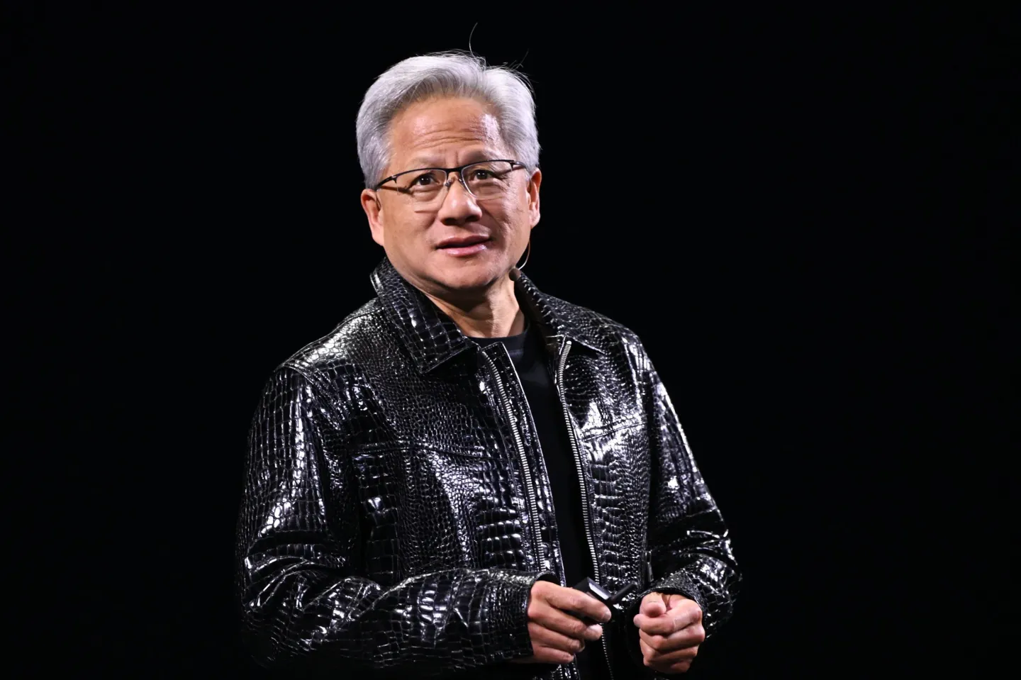 Jensen Huang stands on a stage wearing his trademark black leather jacket