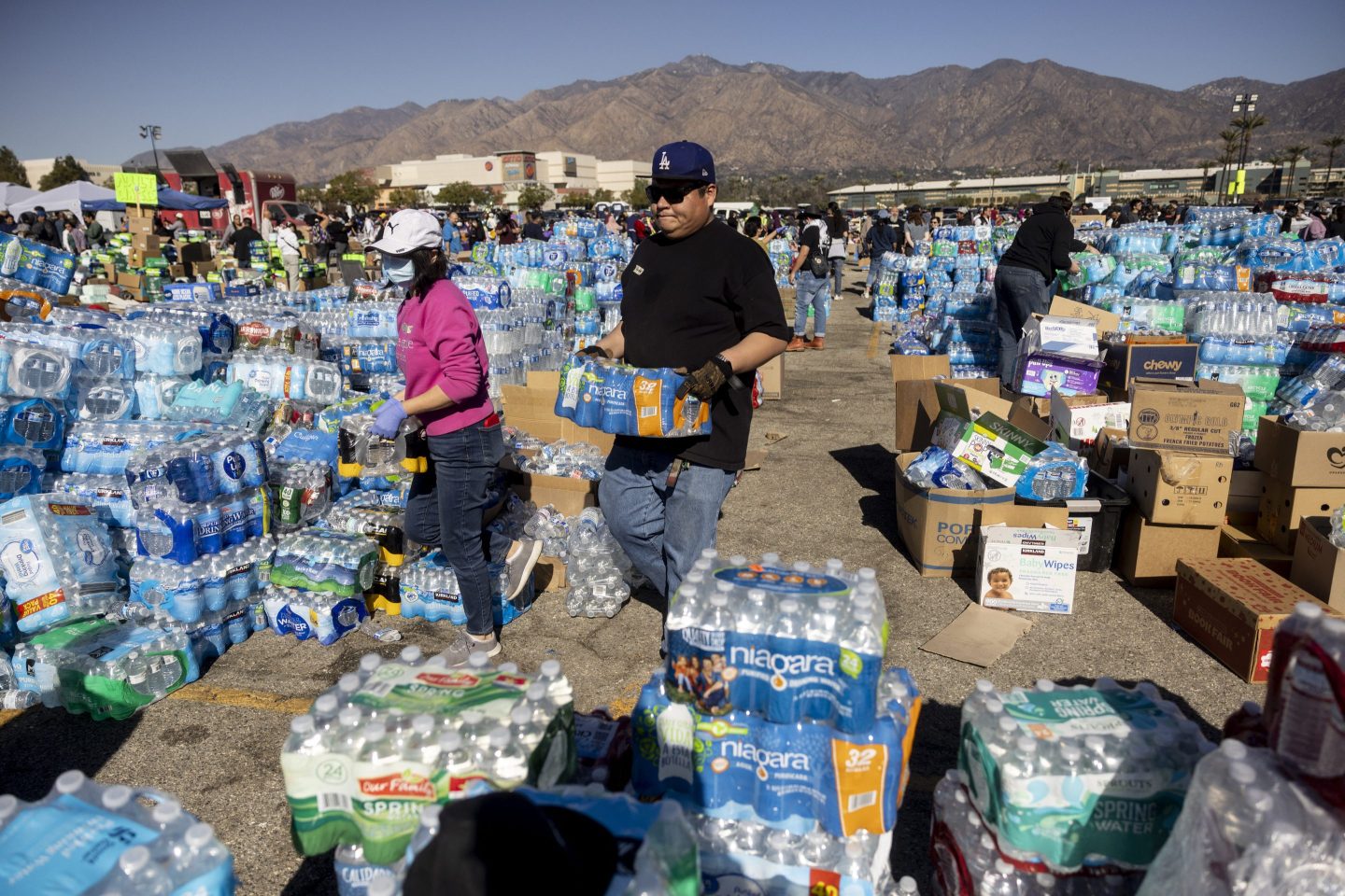 Volunteers carry water for evacuees from the Eaton Fire dwell at a donation center in Santa Anita Park, Arcadia, California, on January 13, 2025. US officials warned &quot;dangerous and strong&quot; winds were set to push deadly wildfires further through Los Angeles residential areas January 12 as firefighters struggled to make progress against the flames. At least 24 people have been confirmed dead from blazes that have ripped through the city, reducing whole neighborhoods to ashes and leaving thousands without homes. (Photo by ETIENNE LAURENT / AFP) (Photo by ETIENNE LAURENT/AFP via Getty Images)