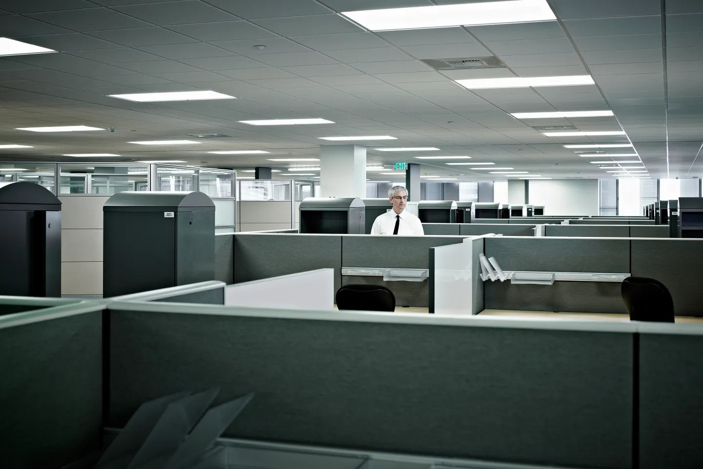 Mature businessman standing alone in cubicle in empty office.