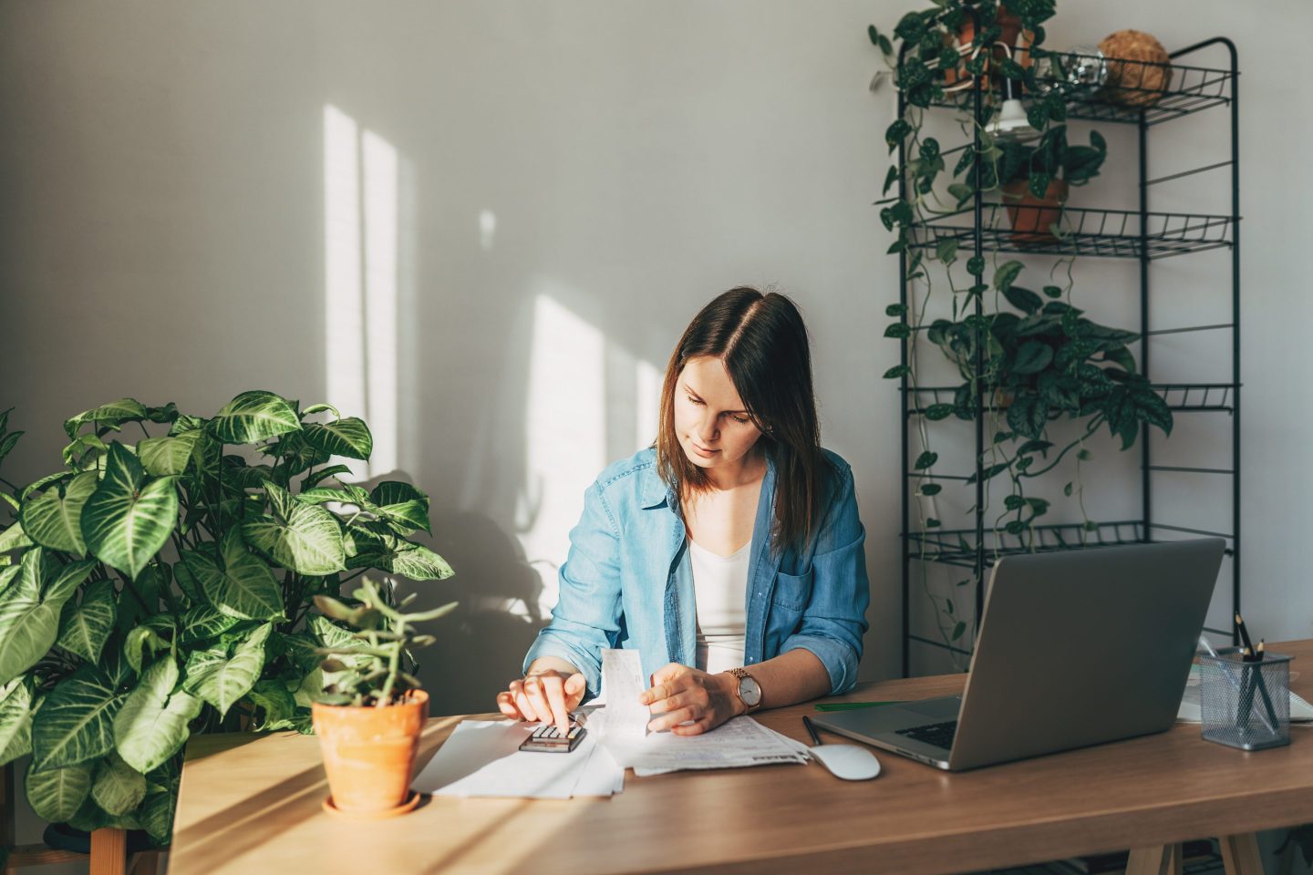 Top view close up woman calculating bills, money, loan or rent payments, using laptop, online banking service, sitting at table, female holding receipt, planning budget, managing expenses, finances.