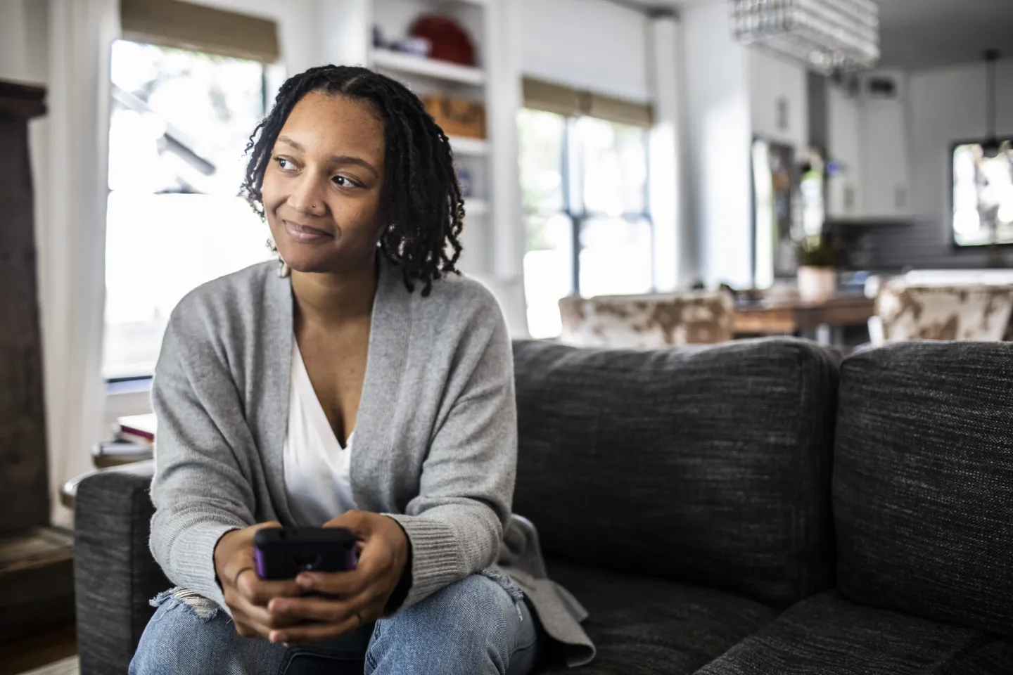 Woman holding smartphone on sofa at home.