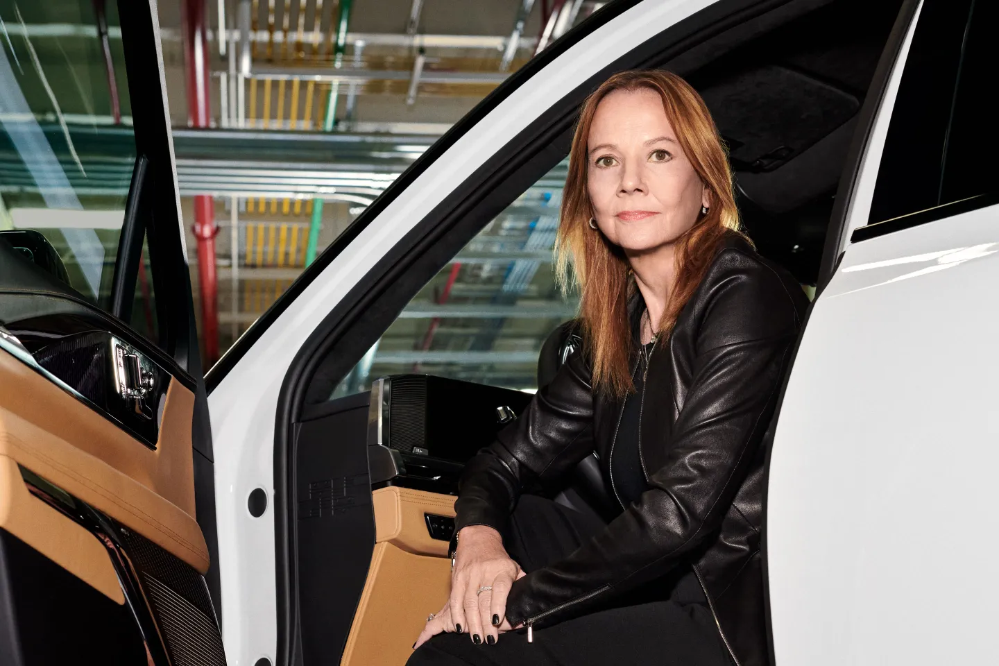 GM CEO Mary Barra sits in the driver's seat of a car.