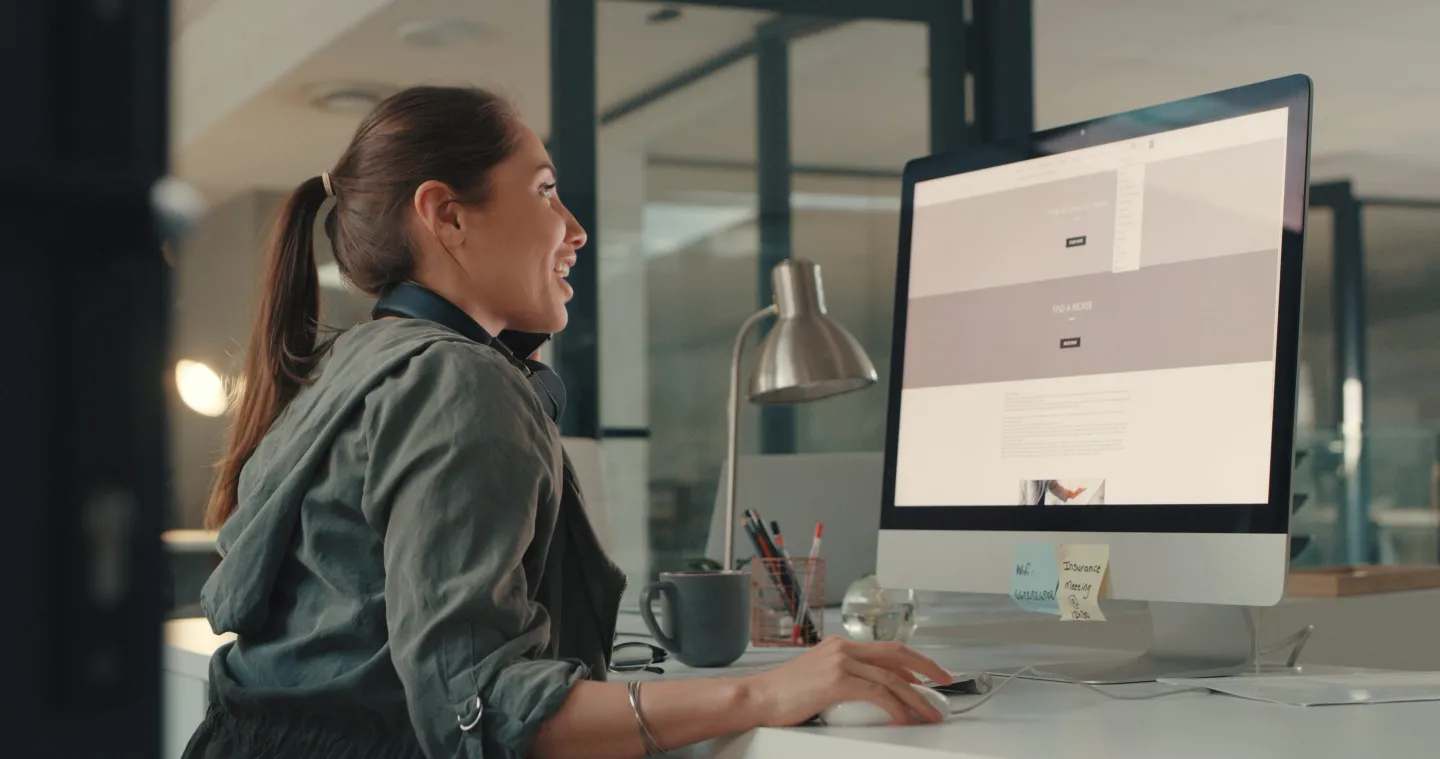 Shot of a young designer talking on a cellphone while working on a computer in an office