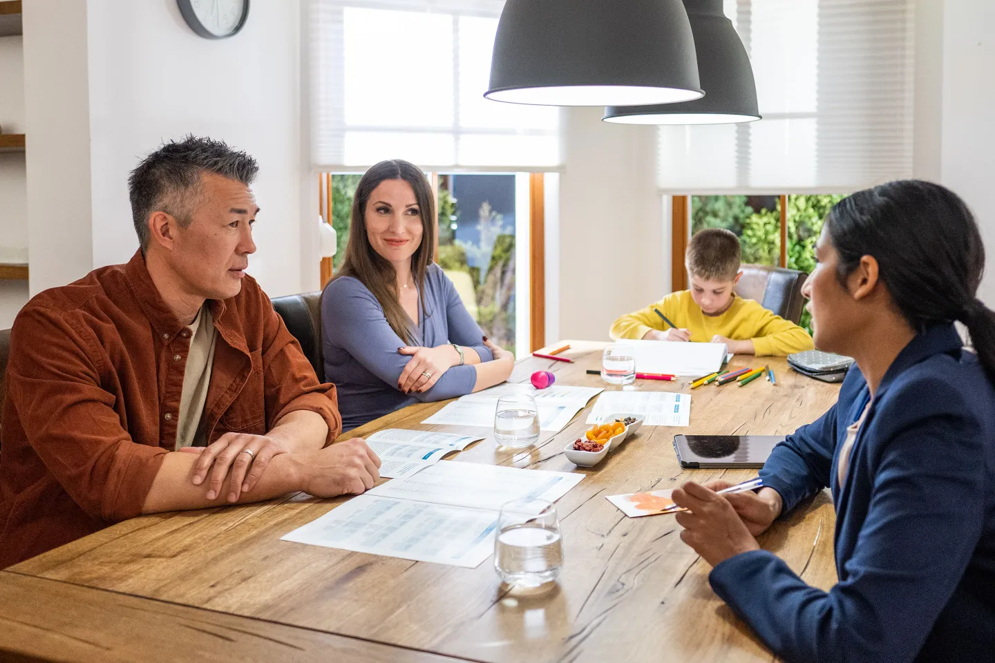 Couple discusses with financial advisor at a kitchen table.