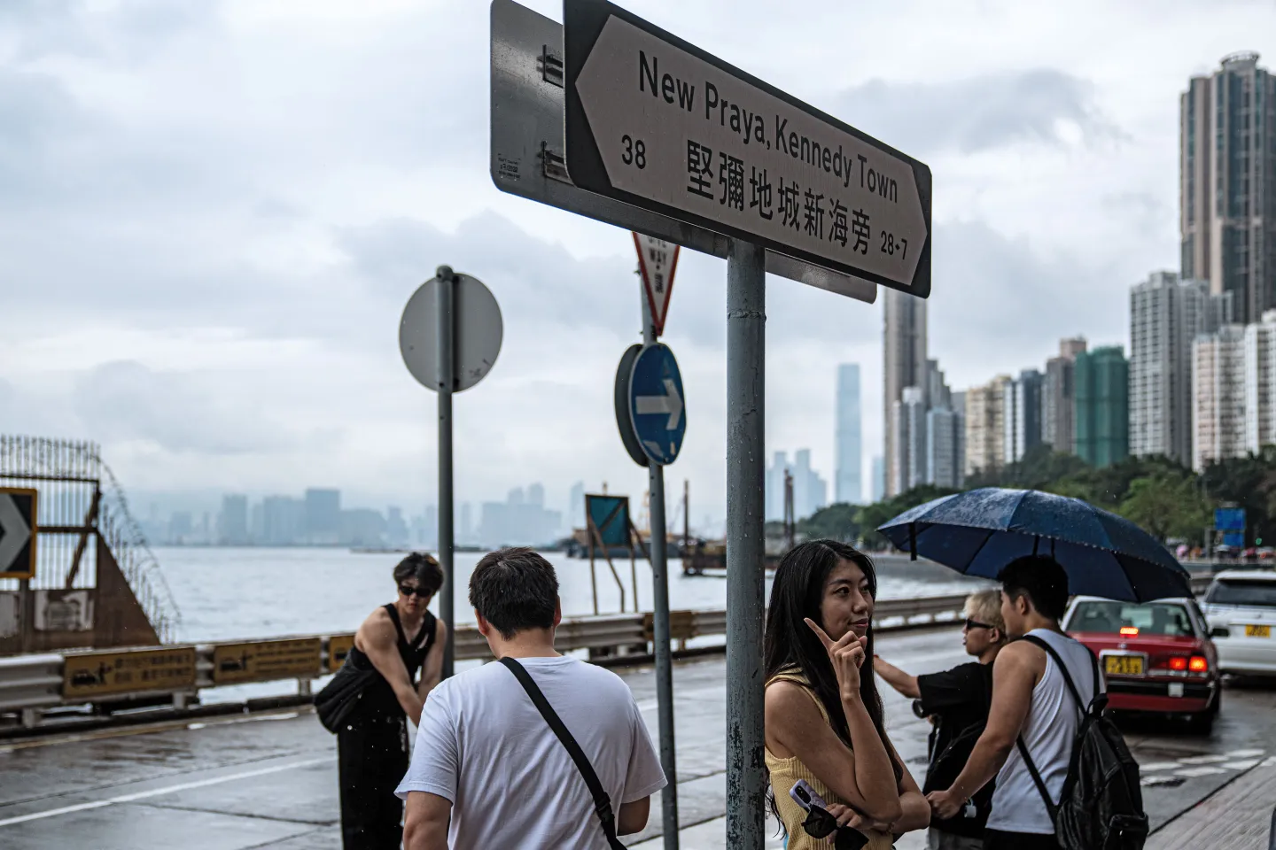 Hong Kong tourists take pictures in front of a sign at the harbor at Kennedy Town.